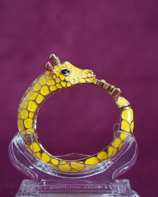 Sculptural hinged bangle shaped like a giraffe wrapping around the wrist, in sunny yellow enamel