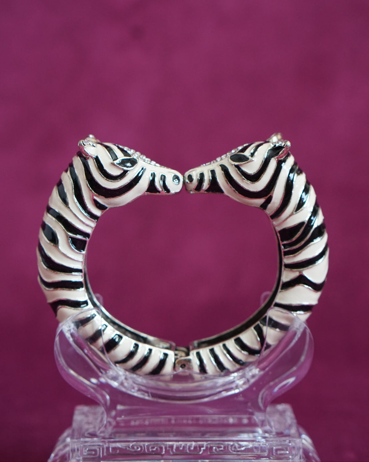Hinged bangle with two zebras meeting nose to nose, in glossy black and white enamel stripes