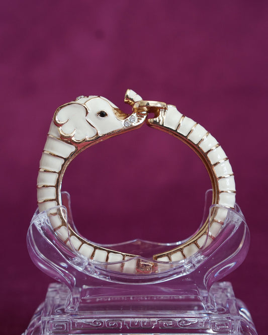Hinged cream enamel bangle shaped like an elephant curling around the wrist, trunk raised
