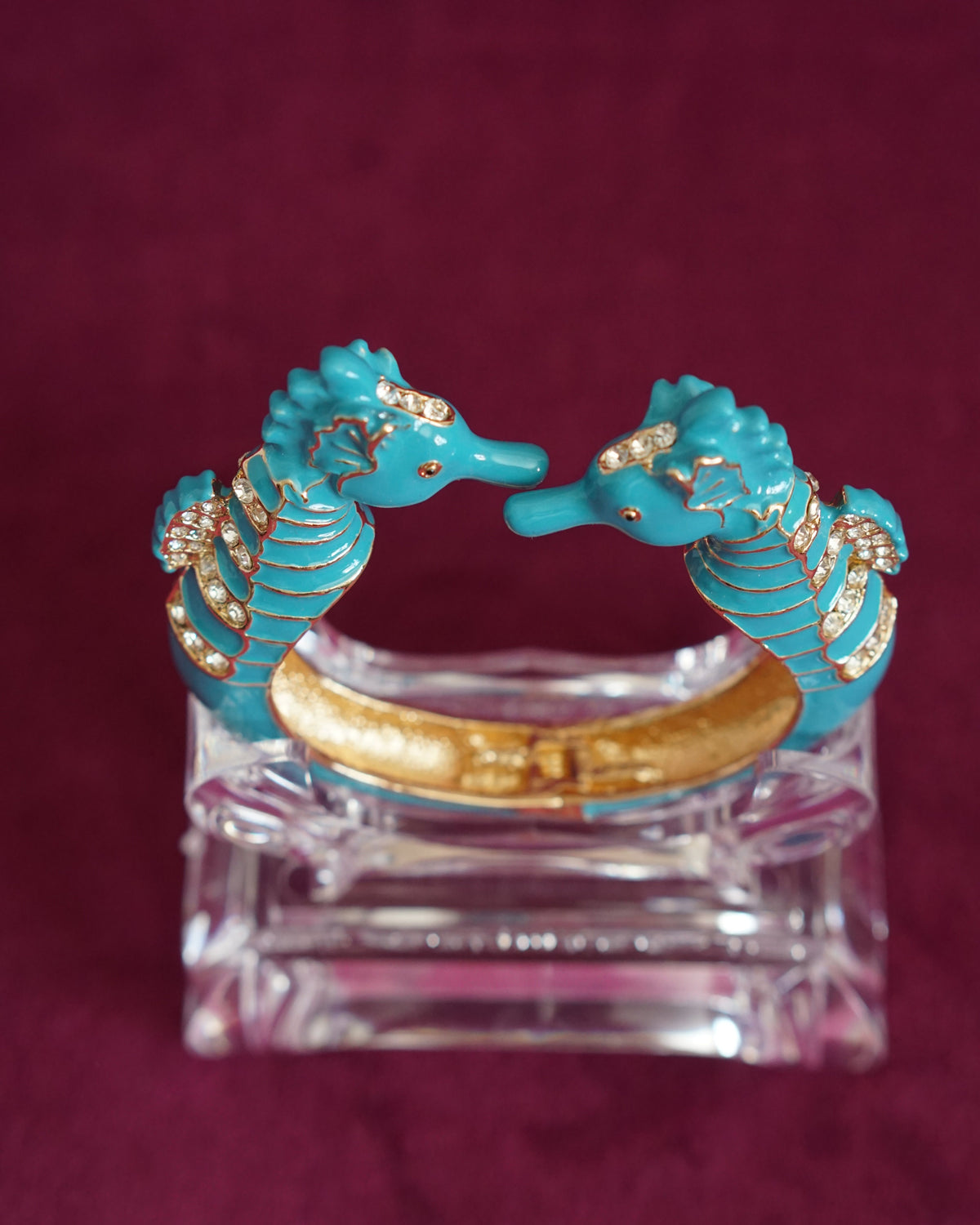 Hinged bangle with two seahorses meeting nose to nose, in bright turquoise enamel