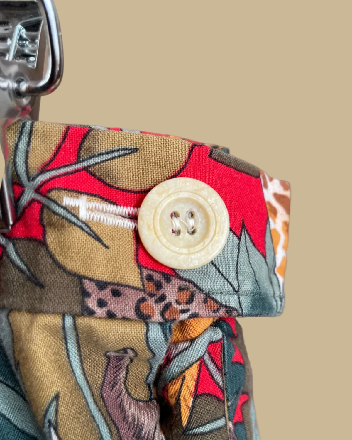 A vintage handmade pleated midi skirt with a jungle safari animal print featuring elephants, giraffes, zebras, and tigers in red, olive, and teal, shown against a kraft background