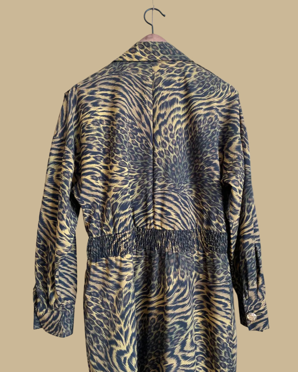 A vintage Leslie Fay double-breasted animal print dress with gold lion-head buttons and epaulette detail, shown against a kraft background