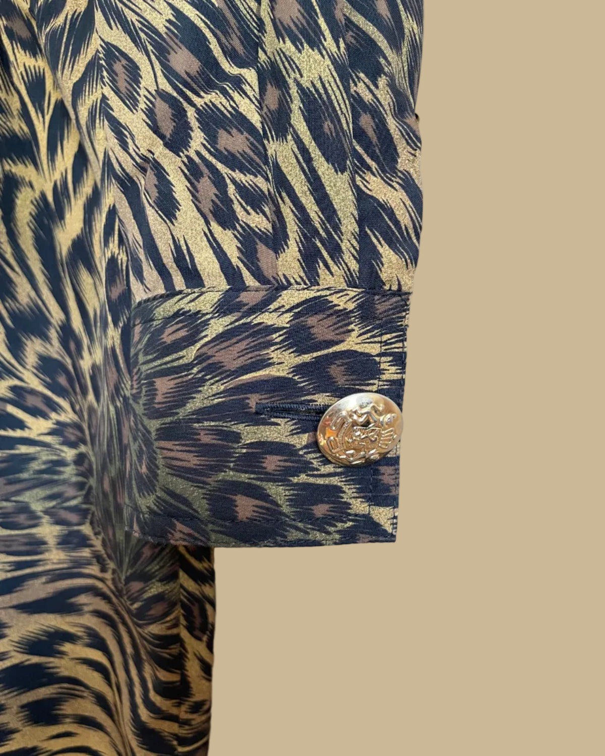A vintage Leslie Fay double-breasted animal print dress with gold lion-head buttons and epaulette detail, shown against a kraft background