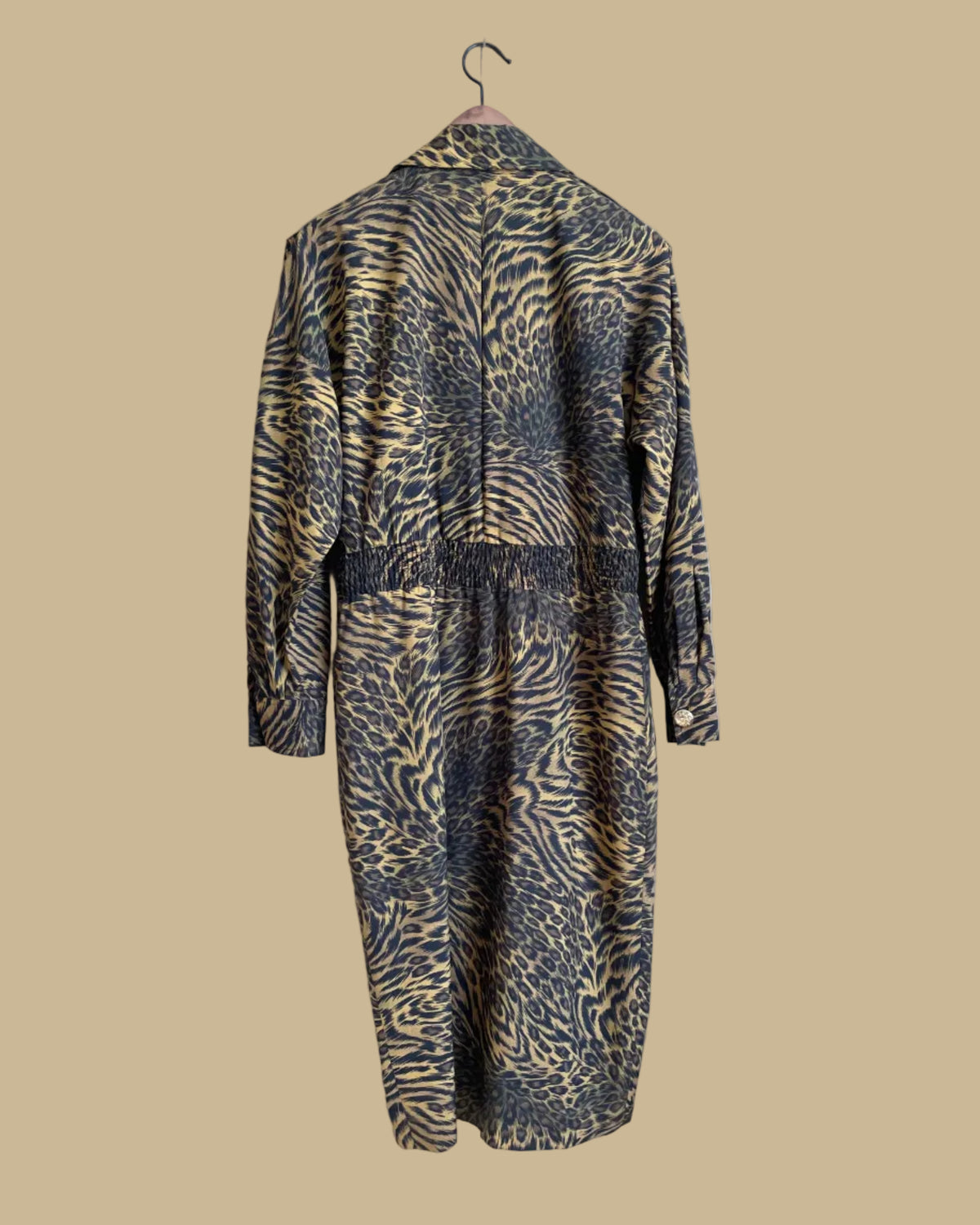 A vintage Leslie Fay double-breasted animal print dress with gold lion-head buttons and epaulette detail, shown against a kraft background