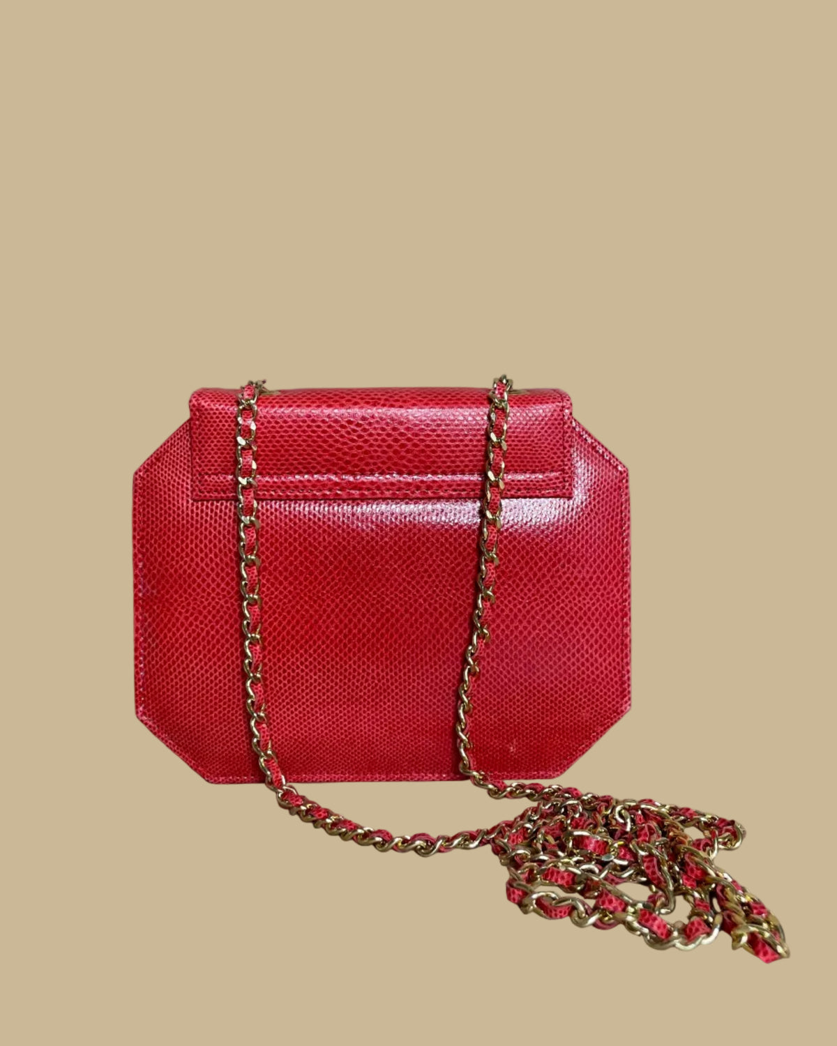 A small red textured snakeskin handbag with a gold-tone panther head clasp, shown on a neutral beige background with its matching chain strap