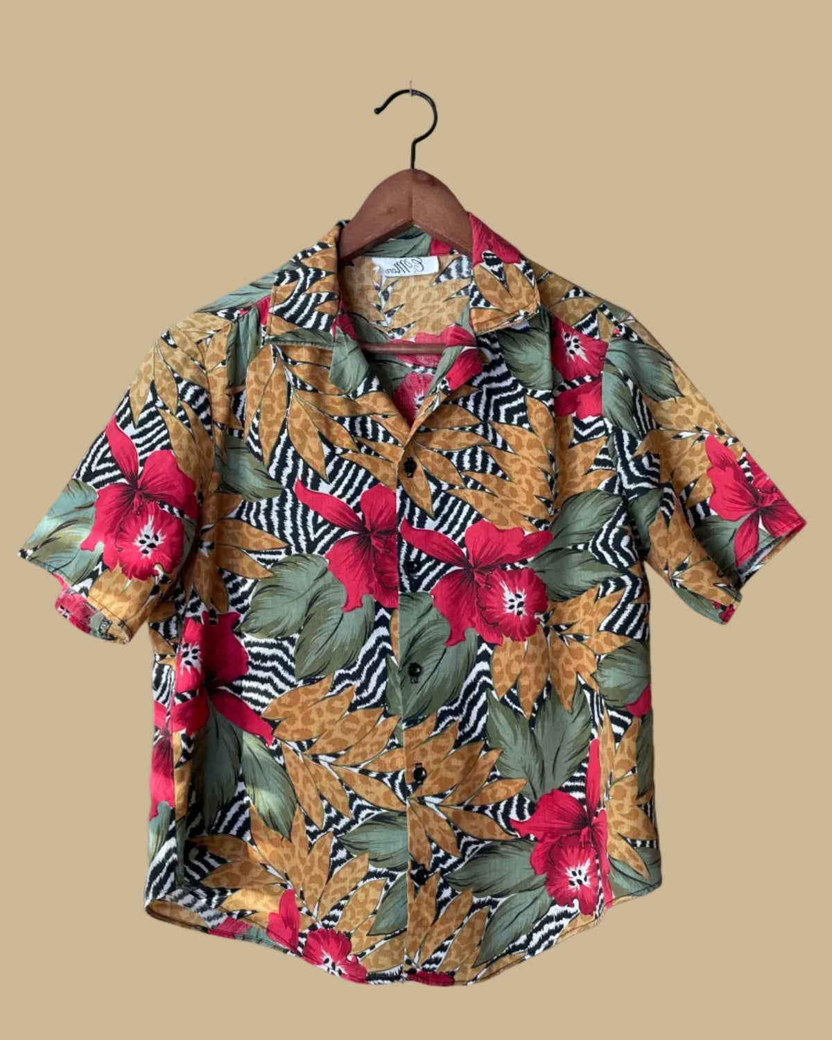 Tropical floral zebra and leopard print camp collar shirt on a hanger against a beige background