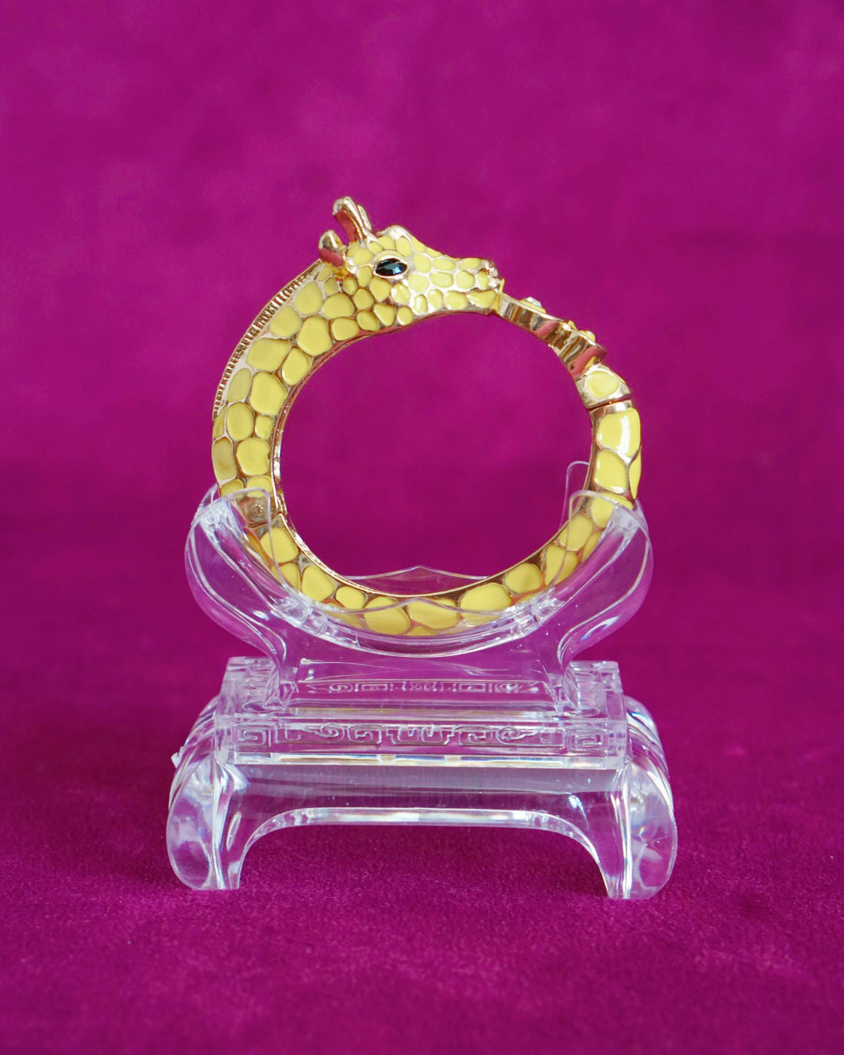 Sculptural hinged bangle shaped like a giraffe wrapping around the wrist, in sunny yellow enamel