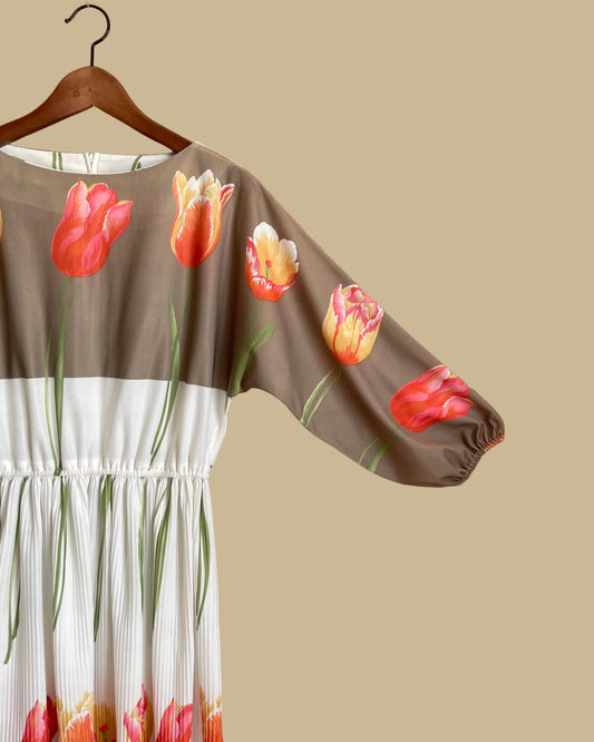 A vintage Herman Marcus tulip print dress in a taupe and cream colorblock with dolman sleeves, shown against a kraft background