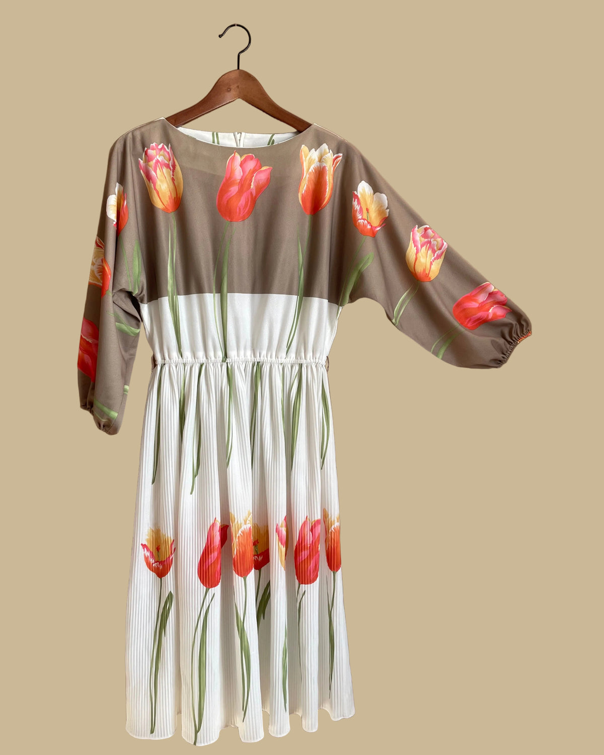 A vintage Herman Marcus tulip print dress in a taupe and cream colorblock with dolman sleeves, shown against a kraft background