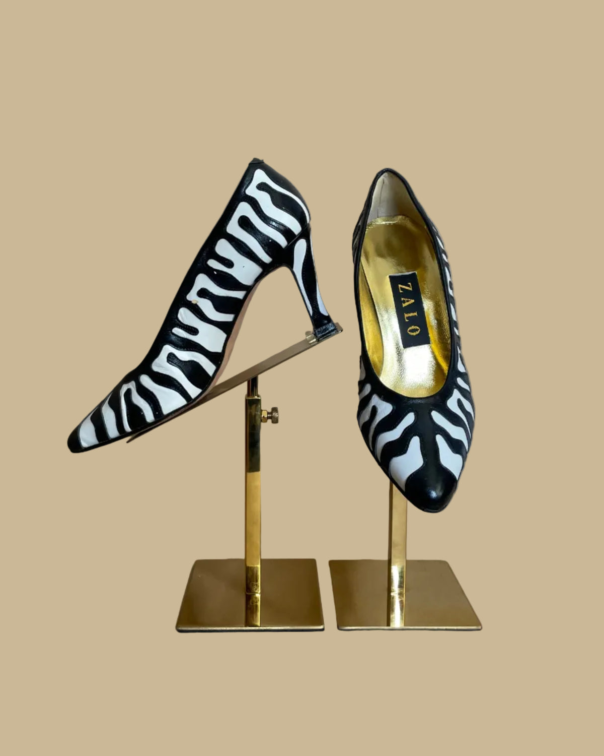 Vintage Zalo black and white zebra print heels on a hanger against a beige background