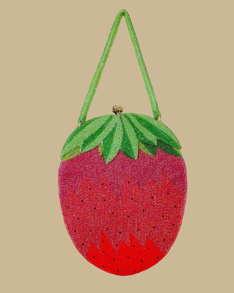 Strawberry-shaped beaded handbag with green top on a beige background