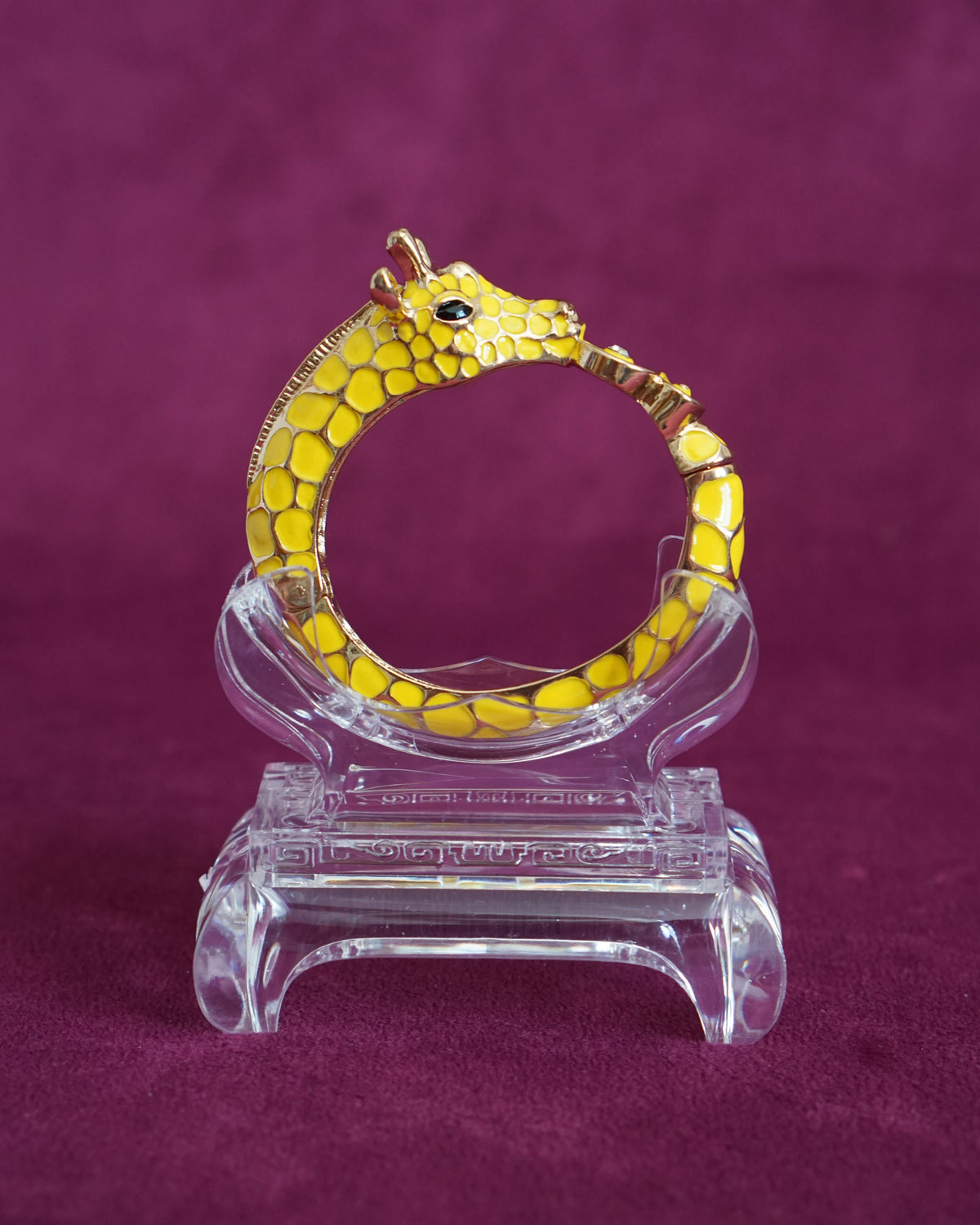 Sculptural hinged bangle shaped like a giraffe wrapping around the wrist, in sunny yellow enamel