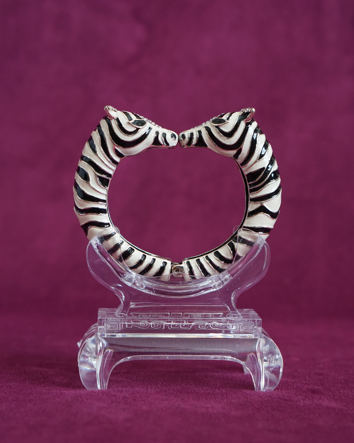 Hinged bangle with two zebras meeting nose to nose, in glossy black and white enamel stripes