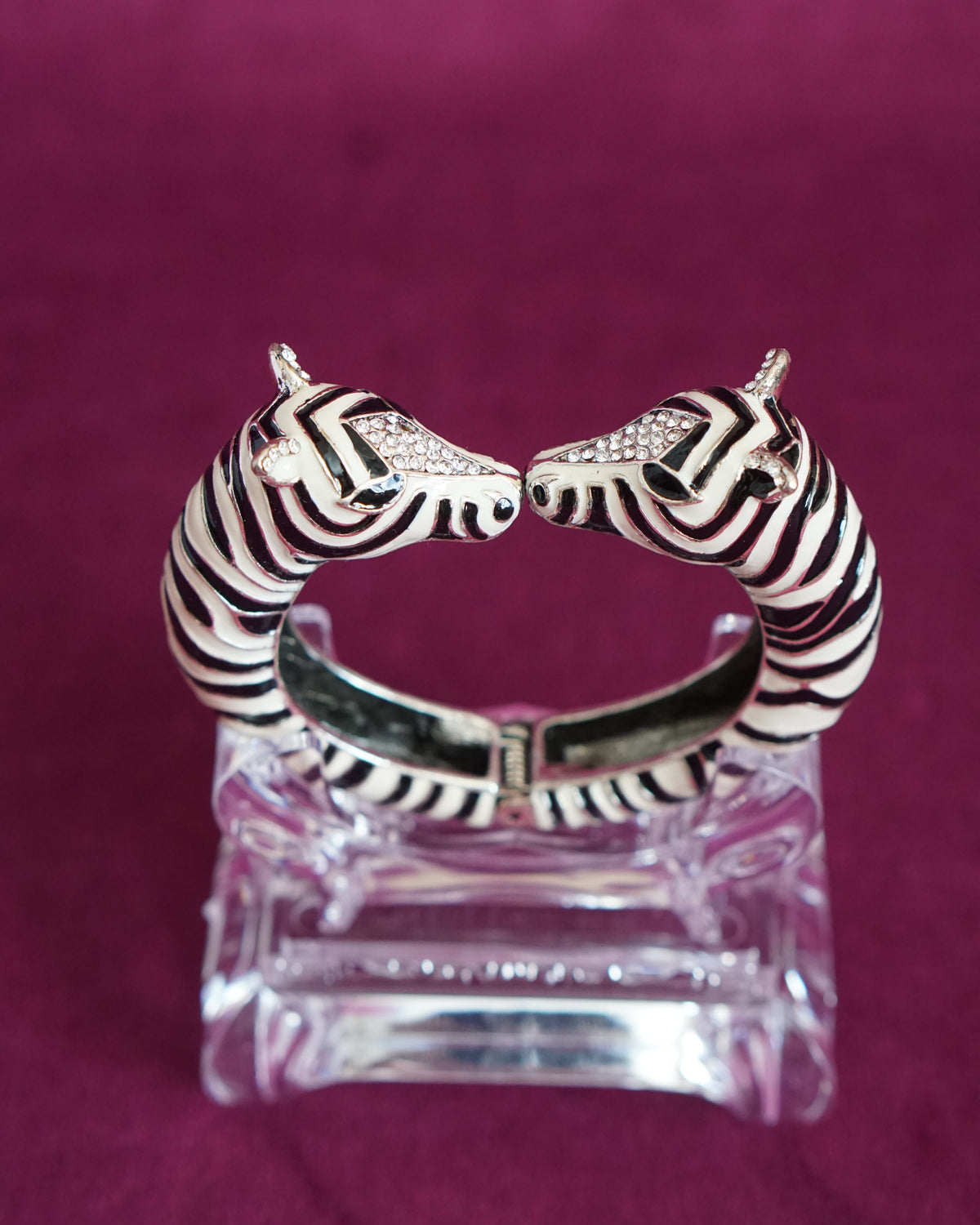 Hinged bangle with two zebras meeting nose to nose, in glossy black and white enamel stripes