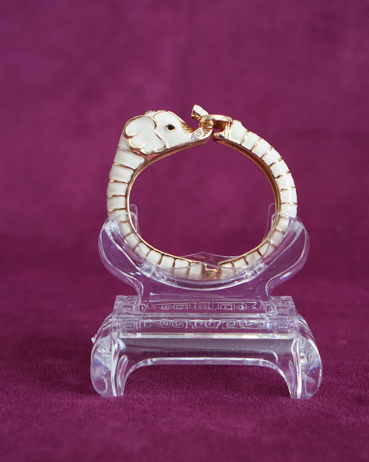 Hinged cream enamel bangle shaped like an elephant curling around the wrist, trunk raised