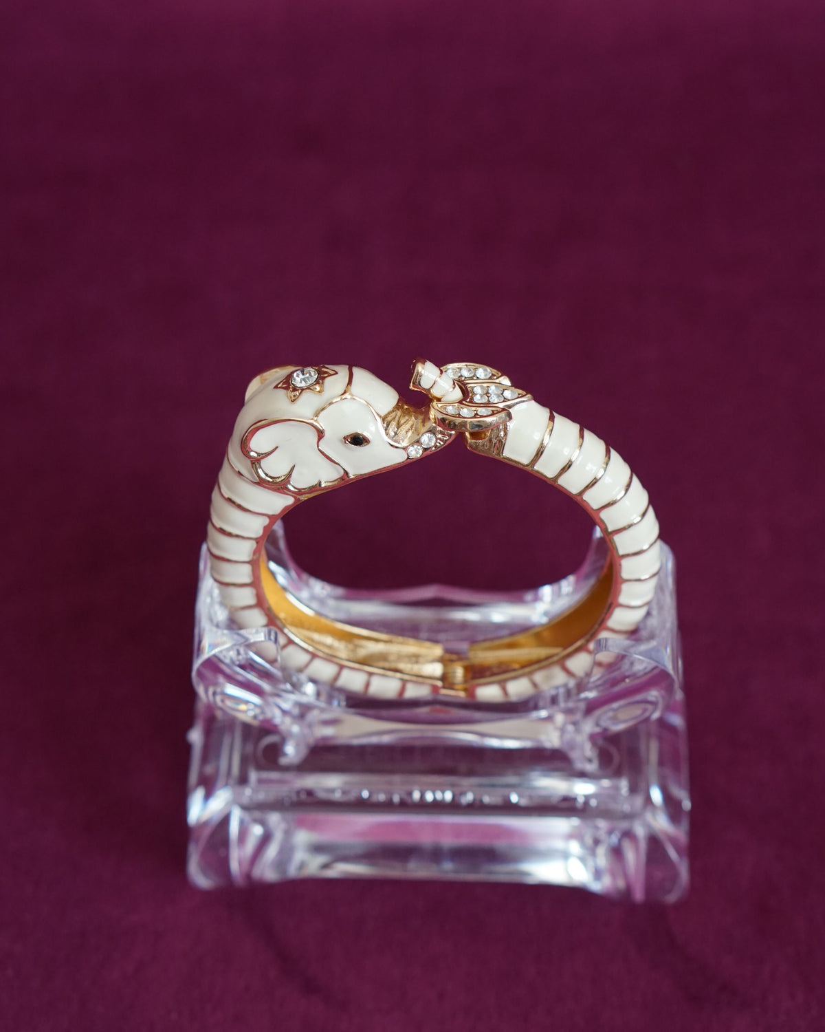 Hinged cream enamel bangle shaped like an elephant curling around the wrist, trunk raised
