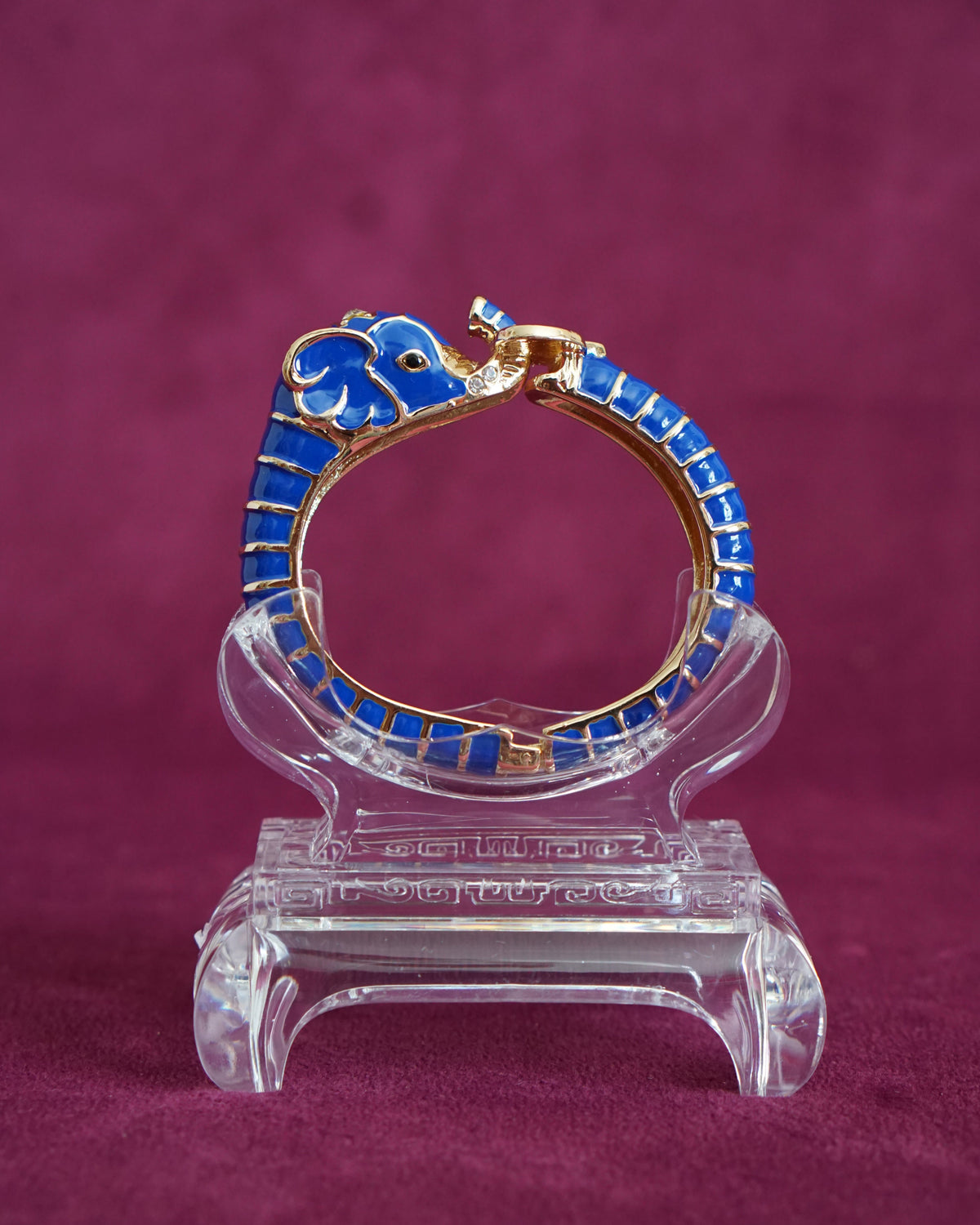 Hinged cobalt blue enamel bangle shaped like an elephant curling around the wrist, trunk raised