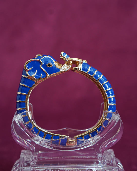 Hinged cobalt blue enamel bangle shaped like an elephant curling around the wrist, trunk raised