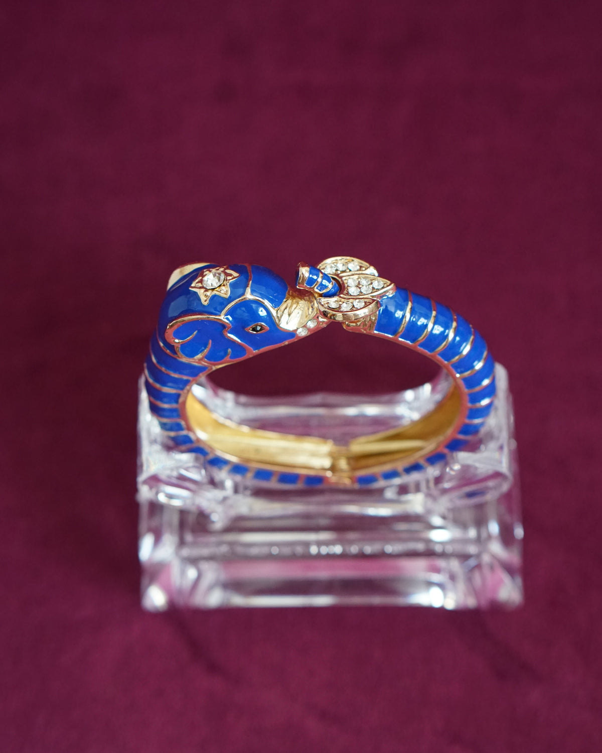 Hinged cobalt blue enamel bangle shaped like an elephant curling around the wrist, trunk raised