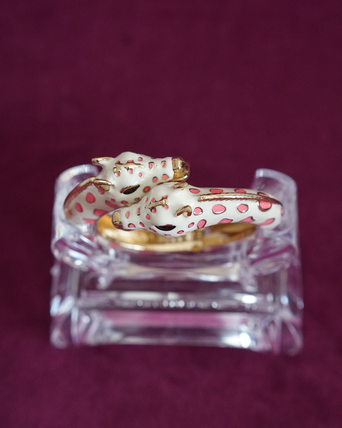 Hinged cream enamel bangle with two giraffes nuzzling at the front of the wrist, soft pink accents