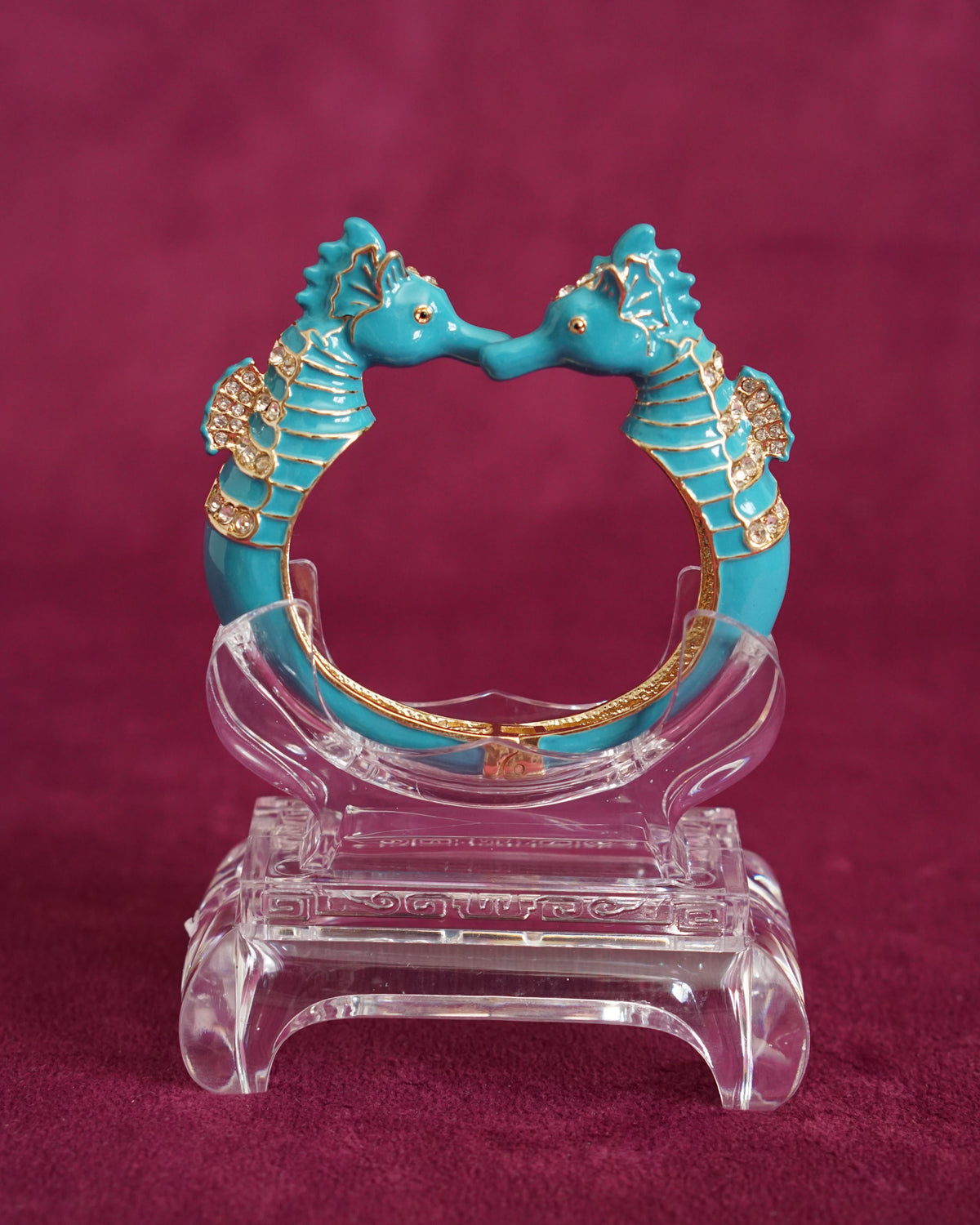 Hinged bangle with two seahorses meeting nose to nose, in bright turquoise enamel