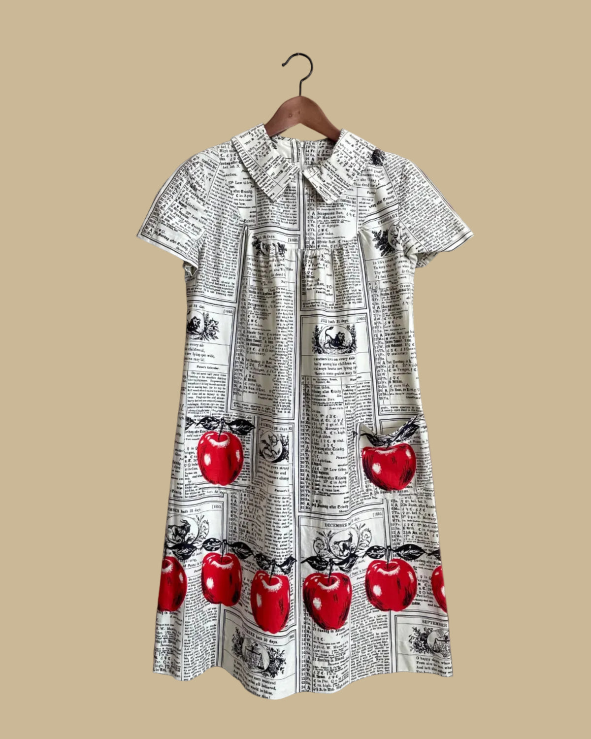 A vintage handmade shift dress with an apple and farmer's-almanac newspaper print, shown against a kraft background