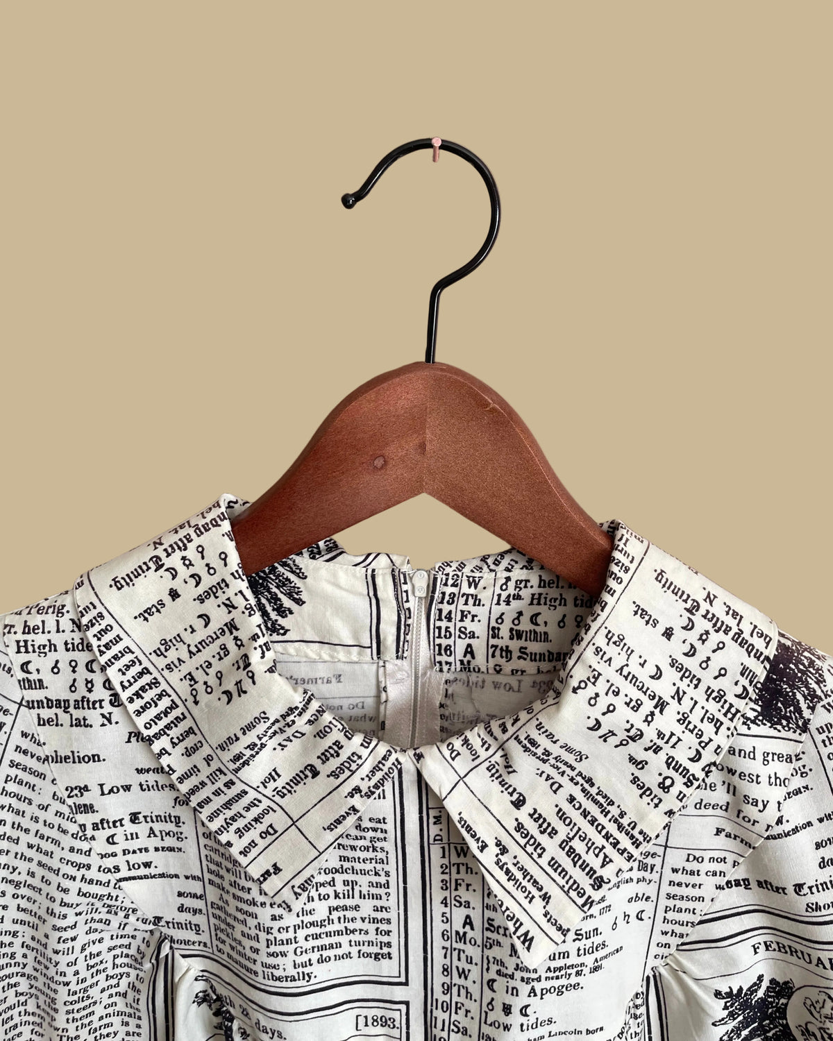 A vintage handmade shift dress with an apple and farmer's-almanac newspaper print, shown against a kraft background
