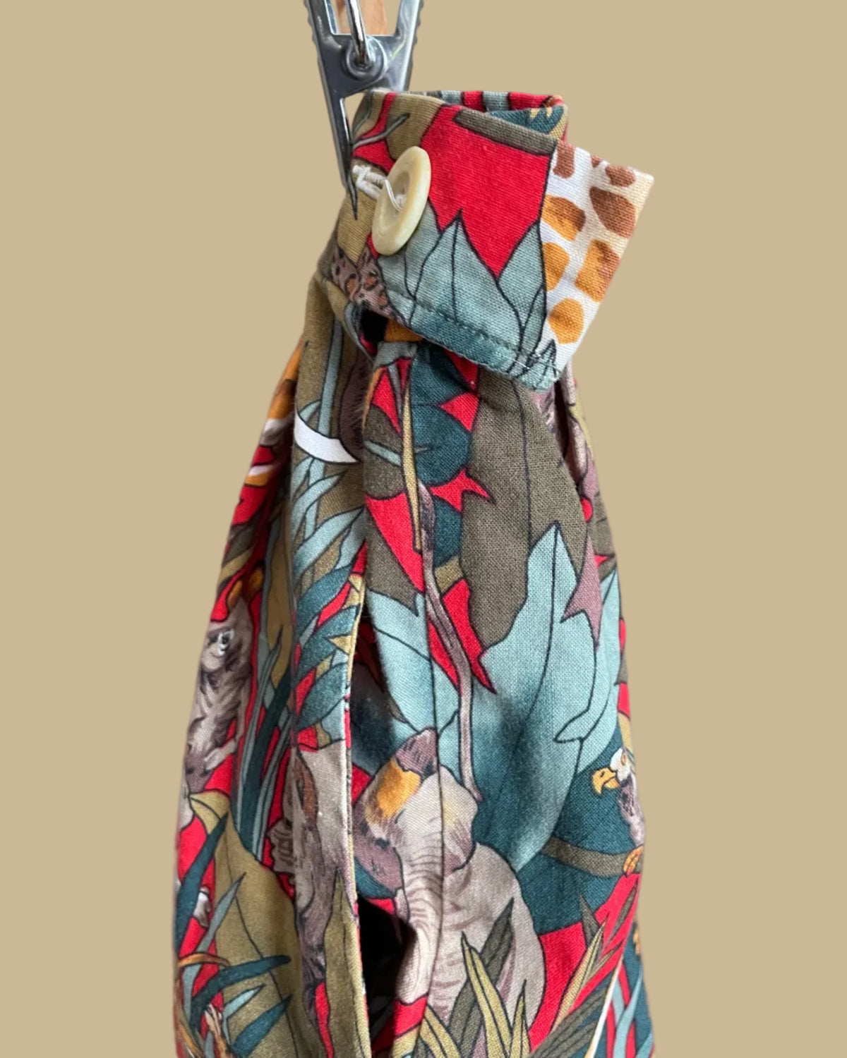 A vintage handmade pleated midi skirt with a jungle safari animal print featuring elephants, giraffes, zebras, and tigers in red, olive, and teal, shown against a kraft background