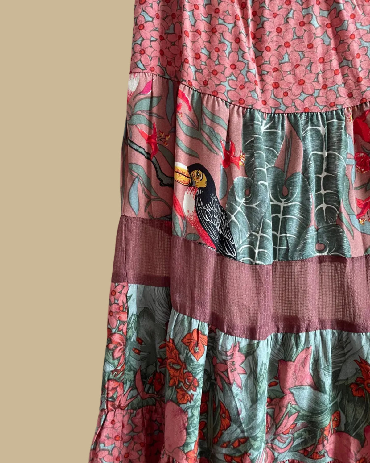 A vintage Carole Little tiered silk skirt with a tropical toucan and floral print in brown, teal, and orange tones, shown against a kraft background