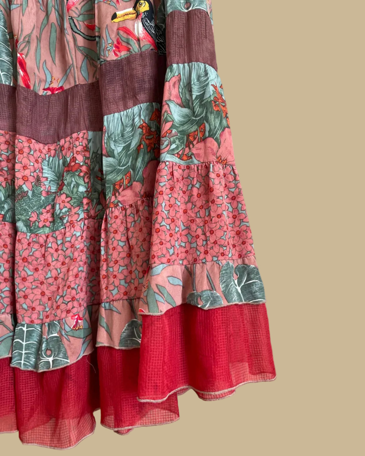 A vintage Carole Little tiered silk skirt with a tropical toucan and floral print in brown, teal, and orange tones, shown against a kraft background