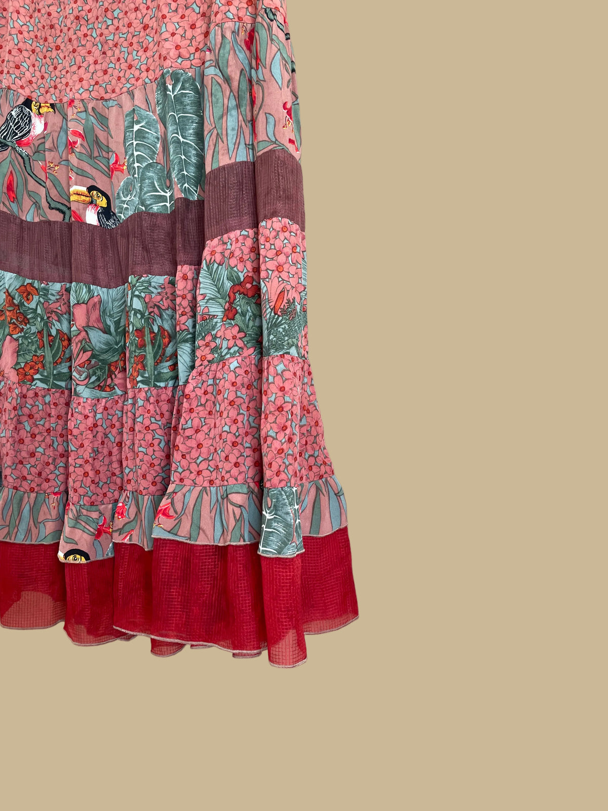 A vintage Carole Little tiered silk skirt with a tropical toucan and floral print in brown, teal, and orange tones, shown against a kraft background