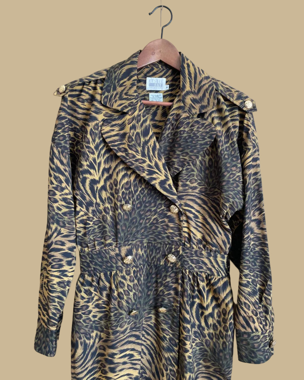 A vintage Leslie Fay double-breasted animal print dress with gold lion-head buttons and epaulette detail, shown against a kraft background