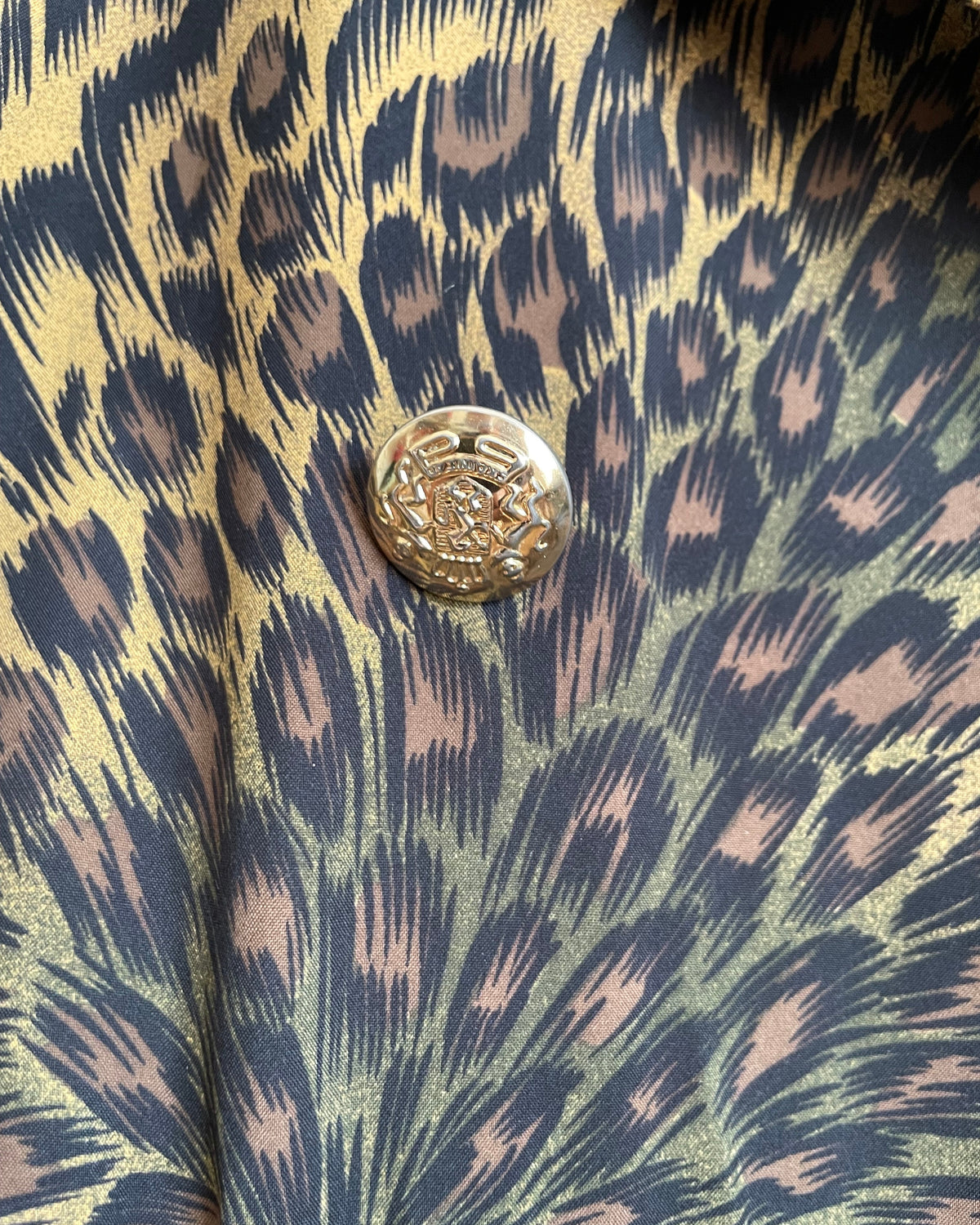 A vintage Leslie Fay double-breasted animal print dress with gold lion-head buttons and epaulette detail, shown against a kraft background