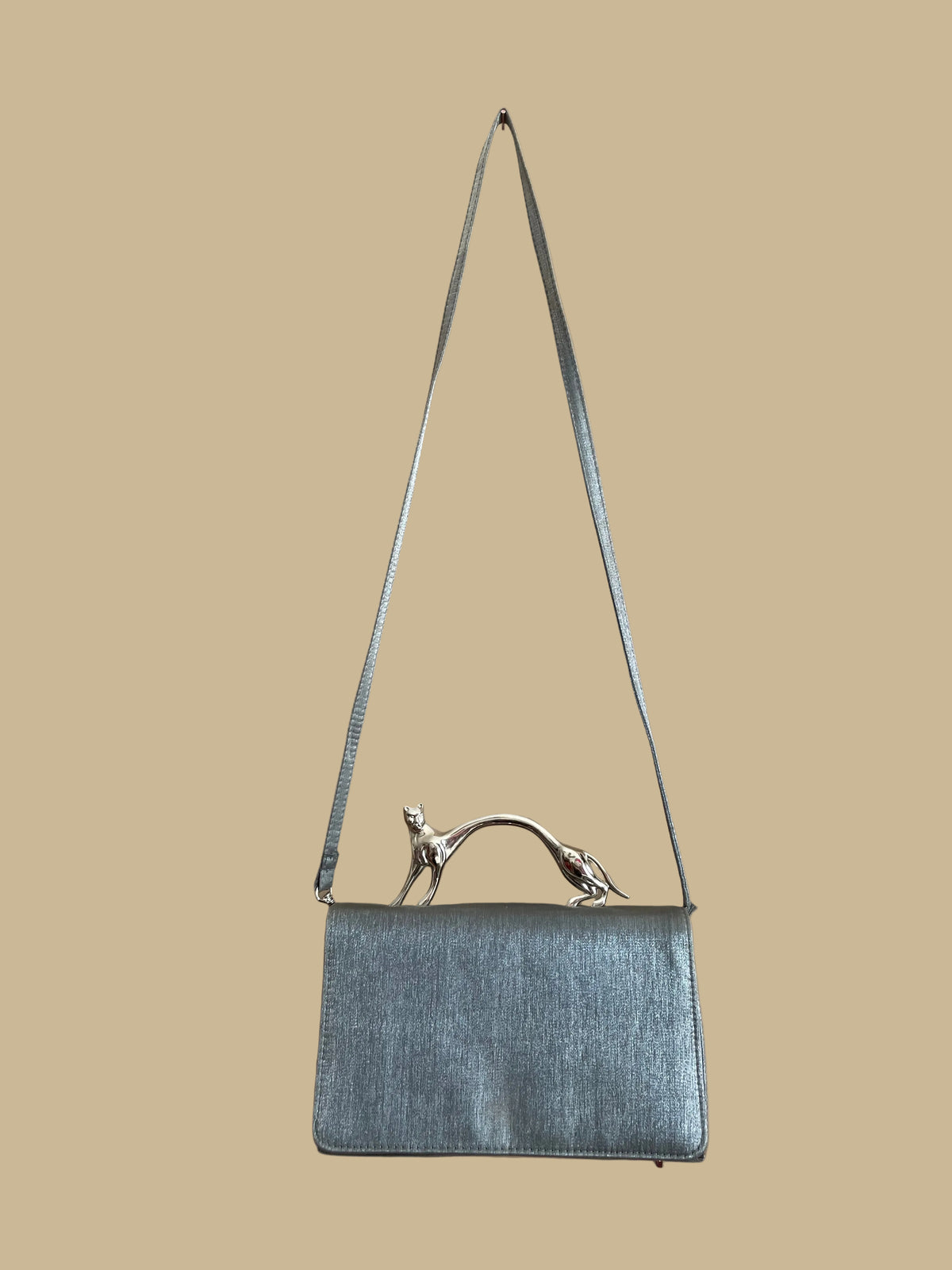 Pewter-silver metallic evening bag with a polished chrome feline handle across the flap