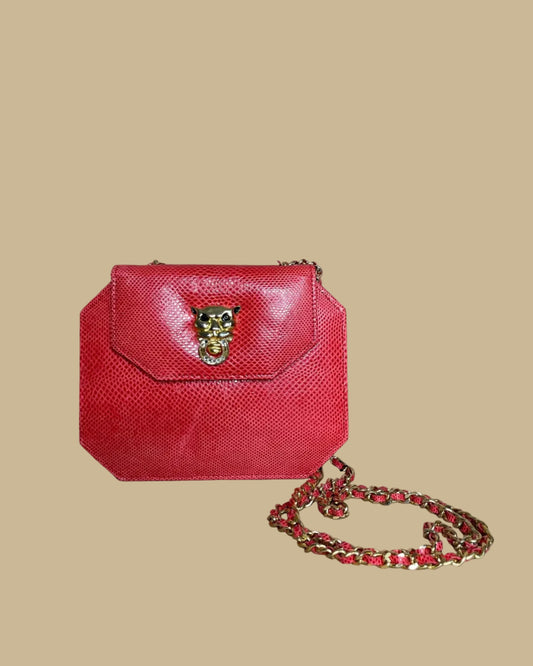 A small red textured snakeskin handbag with a gold-tone panther head clasp, shown on a neutral beige background with its matching chain strap.