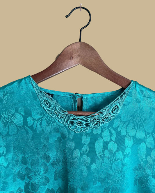 Close-up of the teal floral jacquard blouse fabric texture and pattern