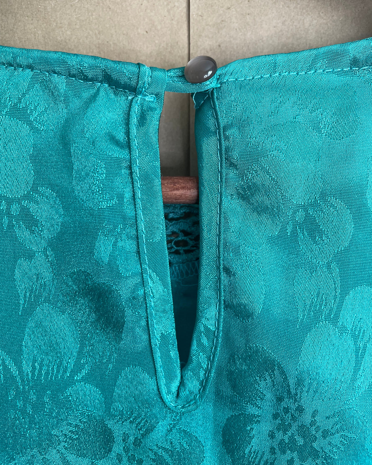 Close-up of the long sleeve and button cuff detail on the teal blouse