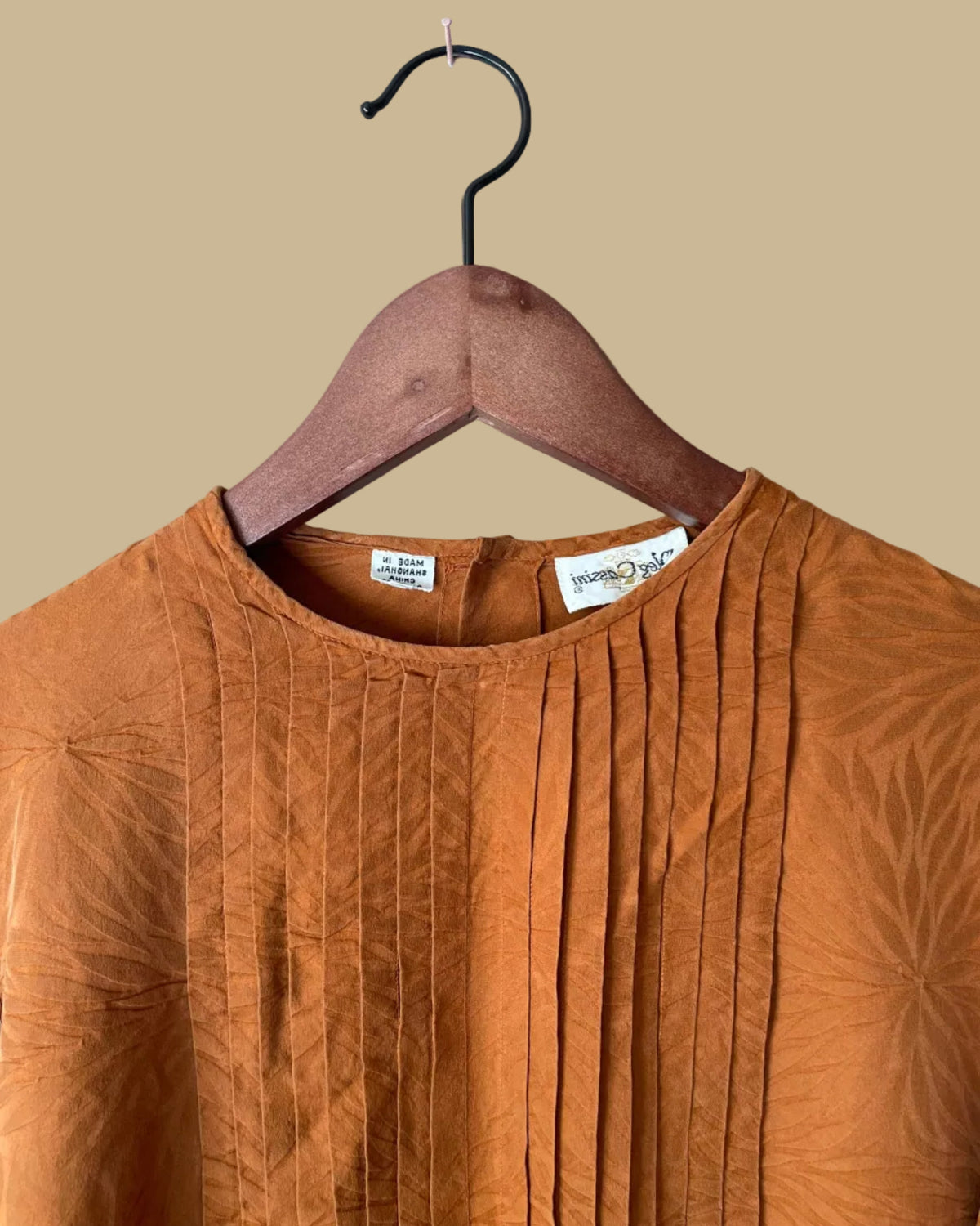 Close-up of the button cuff and sleeve detail on the rust jacquard blouse