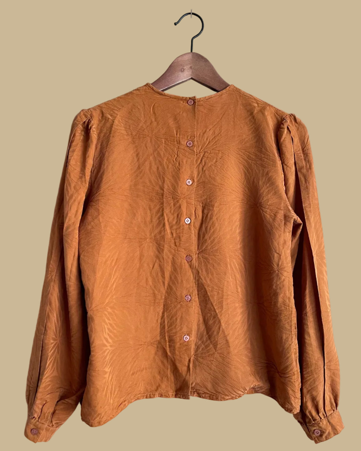 Back view of the rust jacquard pintuck blouse showing the button closure