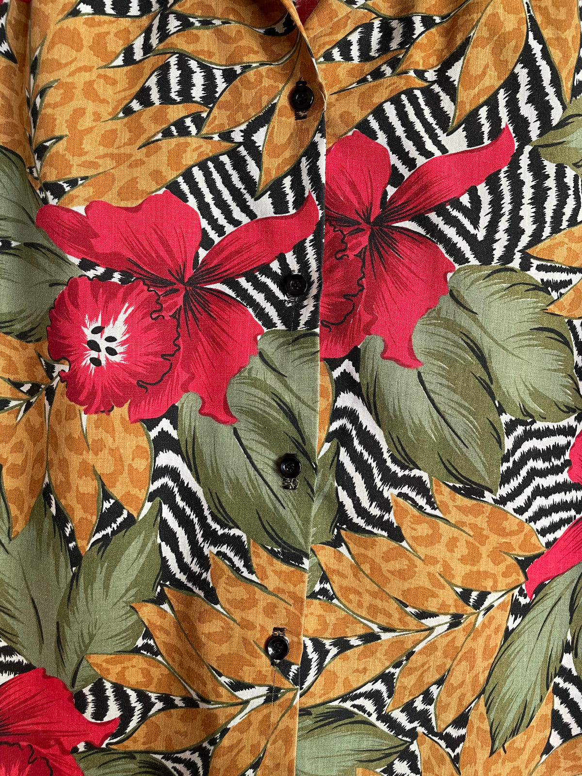 Back view of the tropical floral zebra and leopard print camp shirt on a hanger