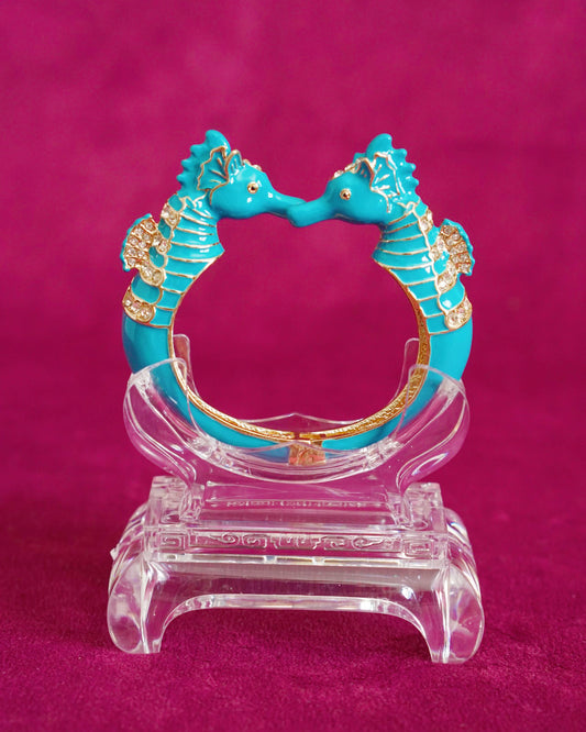 Hinged bangle with two seahorses meeting nose to nose, in bright turquoise enamel