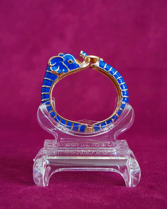 Hinged cobalt blue enamel bangle shaped like an elephant curling around the wrist, trunk raised