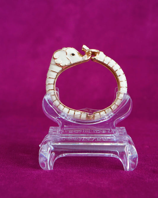 Hinged cream enamel bangle shaped like an elephant curling around the wrist, trunk raised
