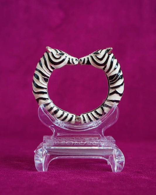 Hinged bangle with two zebras meeting nose to nose, in glossy black and white enamel stripes