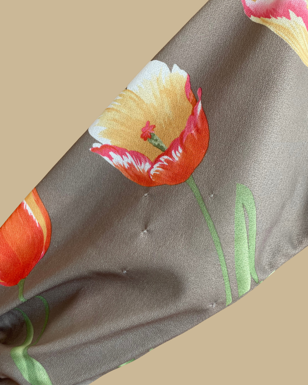 A vintage Herman Marcus tulip print dress in a taupe and cream colorblock with dolman sleeves, shown against a kraft background