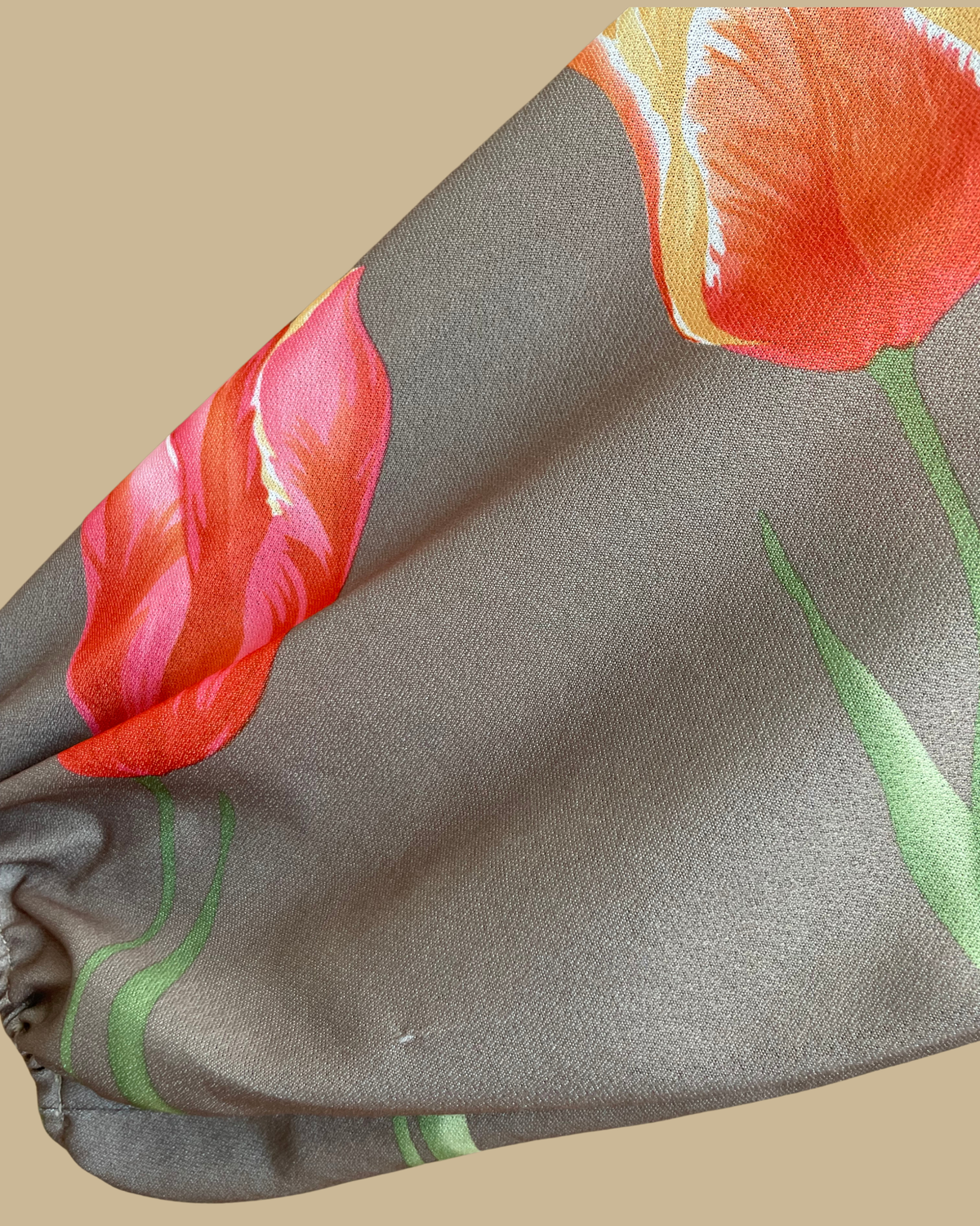 A vintage Herman Marcus tulip print dress in a taupe and cream colorblock with dolman sleeves, shown against a kraft background