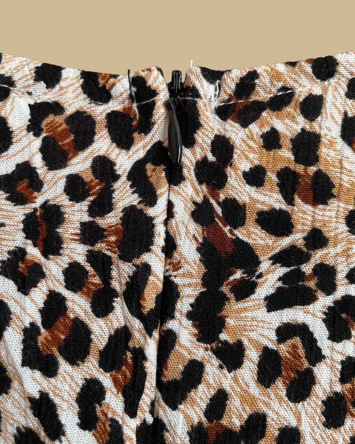 A Very J leopard print romper with a tie-neck V and bell sleeves, shown against a kraft background