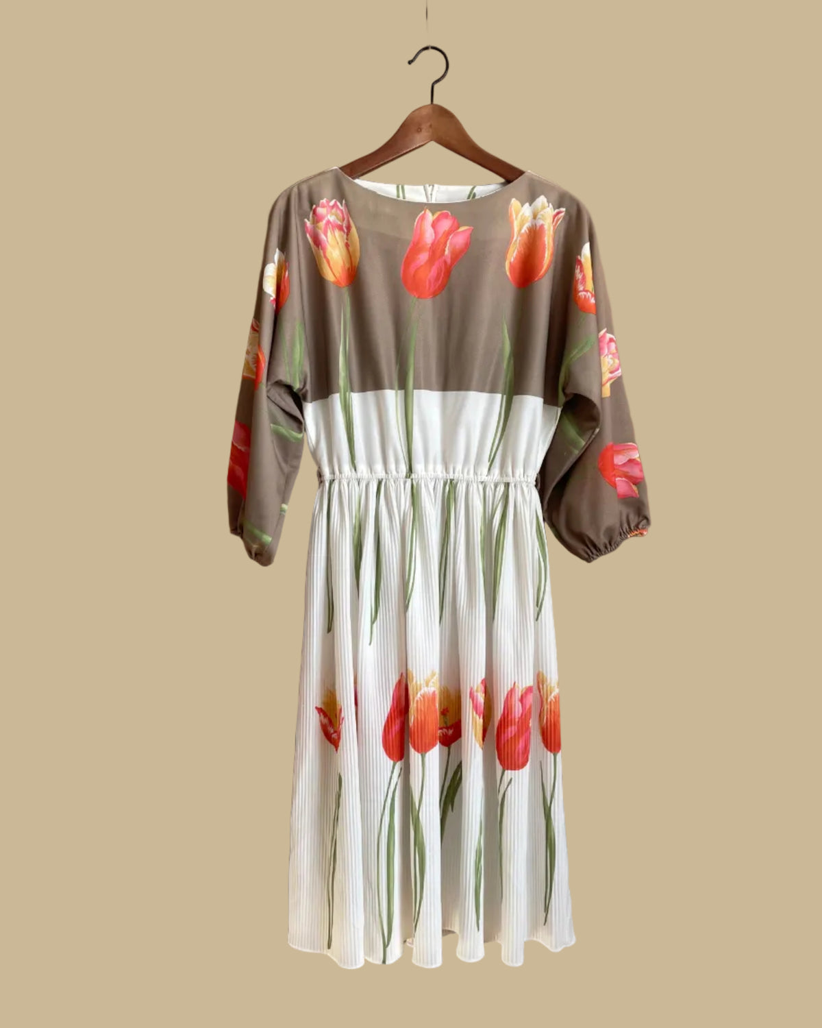 A vintage Herman Marcus tulip print dress in a taupe and cream colorblock with dolman sleeves, shown against a kraft background