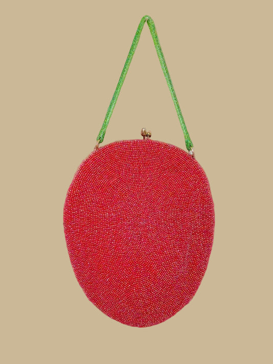 Red beaded handbag with a green strap on a beige background